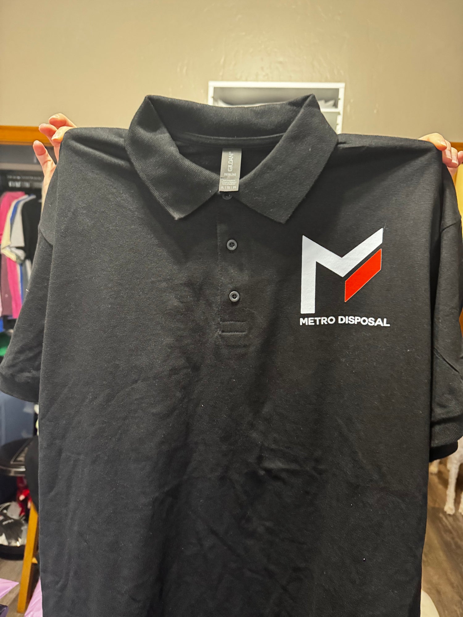 Black polo shirt with red and white metro disposal logo on front