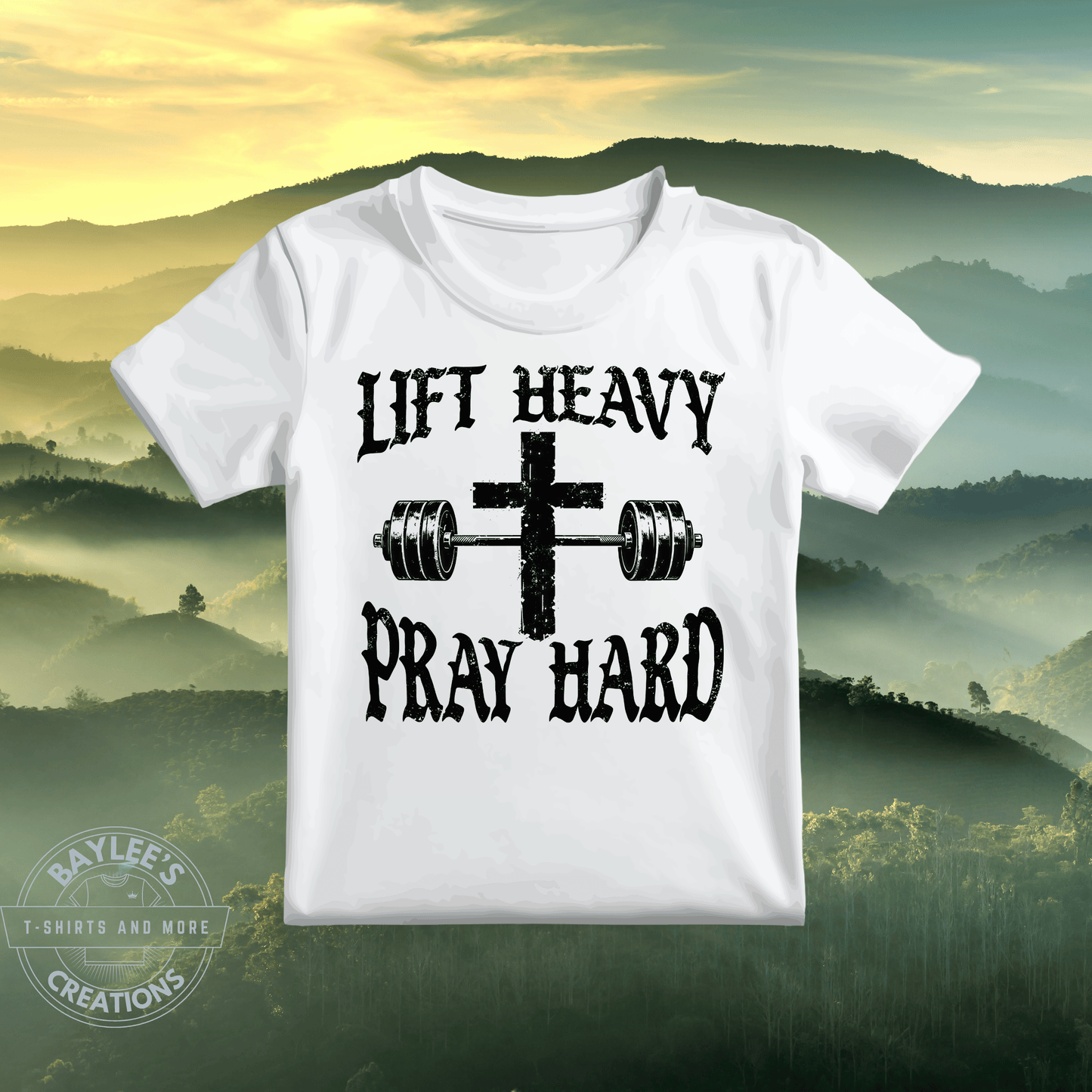 White t-shirt with 'Lift Heavy Pray Hard' text and cross graphic on a scenic background
